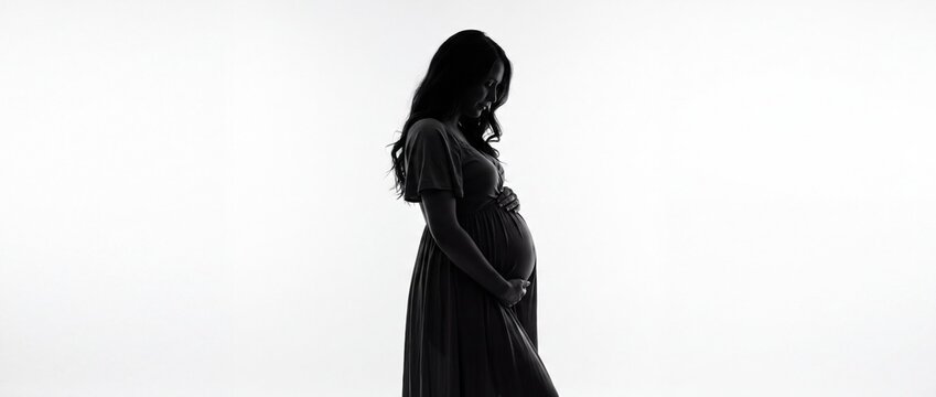 Silhouette of thoughtful pregnant woman with her hands on her belly, symbolizing maternal care and expecting mother