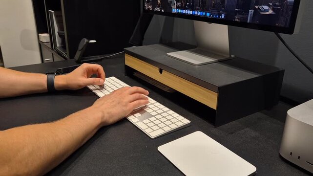 Person typing and using a wireless mouse at a modern computer workstation
