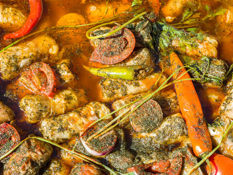 traditional Romanian cabbage rolls - sarmale simmering in a rich, red tomato and pepper sauce garnished with fresh herbs and chili peppers