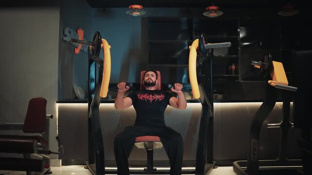 Wide angle view of a muscular bearded man performing seated plate loaded chest press machine exercise for upper body strength and pectoral muscle building in a modern gym.