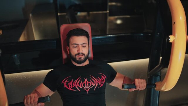 Athletic male athlete pushing handles on an incline lever chest press machine focusing on pectoralis major development inside a fitness center.