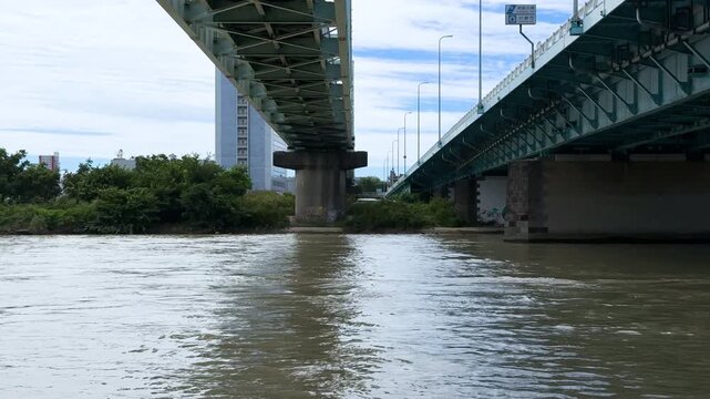Swollen Tama River Flowing Between Two Large Urban Bridges