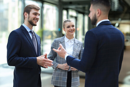 Three young businessmen standing discussing business at an office meeting.