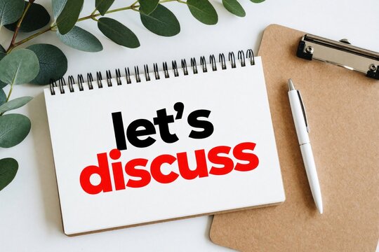 Open notebook with lets discuss text on white page. Green eucalyptus leaves, white pen, wooden clipboard on desk. Concept for business meeting, team talk, brainstorming ideas management strategy in