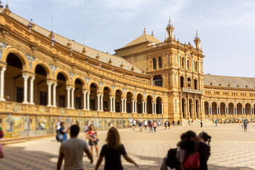 Plaza de España semicircular building showcasing Renaissance Revival and Moorish styles with arches, columns, and ceramic details, while tourists explore the monumental landmark © photoopus