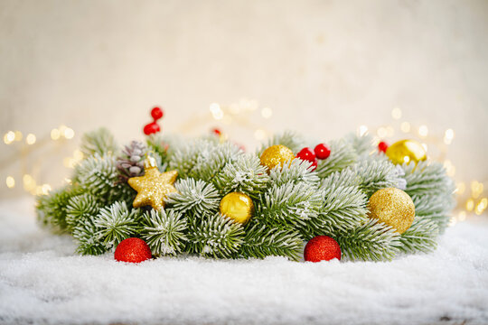 Christmas Holiday background with snow, fir tree and decorations with christmas light behind. Christmas red, white and golden balls on a winter festive background.
