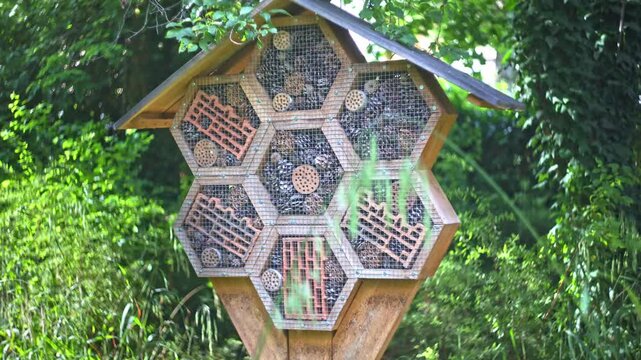 Wooden insect hotel in a shape of honeycomb in a park.