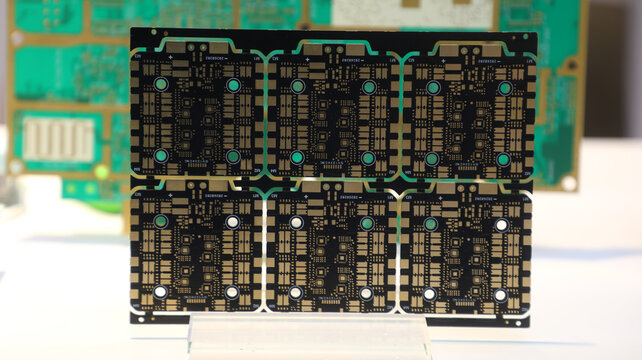 PCB in a black printed array sits on a small clear display stand.