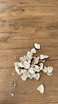 Hands finishing slicing fresh wild birch bolete mushroom with a knife on wooden background. Ideal B-roll for autumn cooking recipe, food prep and foraging concept. 9:16 vertical video.