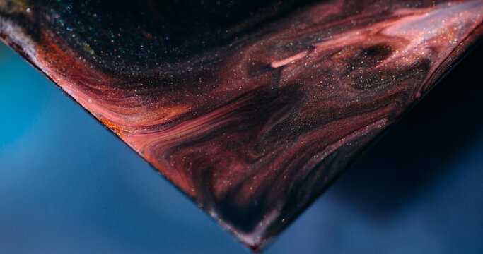 Sparkling paint. Acrylic particles. Defocused blue orange purple color shiny art triangle mix texture spilling on abstract background.