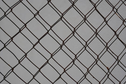 Overlapping chain link fences with geometric diamond pattern against a gray background