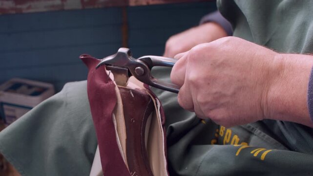 Cobbler service. Professional shoemaker. Unrecognizable craftsman hands working with metal pliers at factory for handmade occupation.