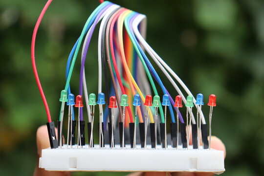 Colorful jumper wires with light emitting diodes connected to a breadboard for electronics prototyping and circuit building