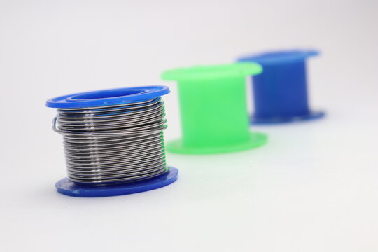 Close up of solder wire spool with empty blue and green spools blurred in background