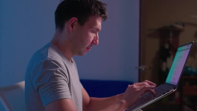 Close-up right hand adjusting tilted laptop mounted on adjustable metal hinge bracket with visible cables, reflecting soft light on aluminum housing in indoor workspace