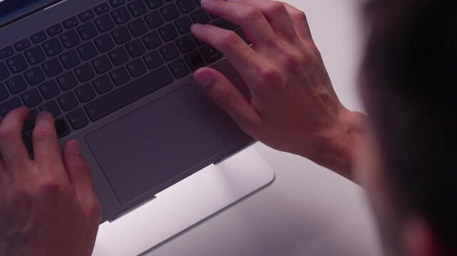 Close-up right hand adjusting tilted laptop mounted on adjustable metal hinge bracket with visible cables, reflecting soft light on aluminum housing in indoor workspace