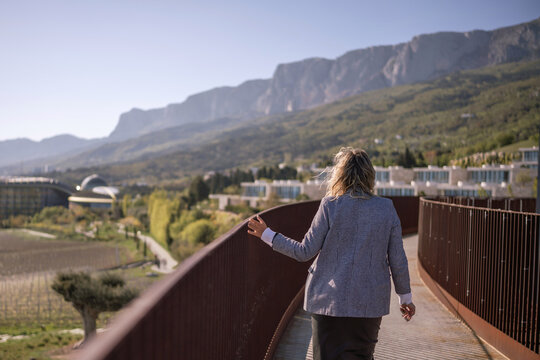 Woman walking architecture resort balcony, enjoying scenic mountain landscape view