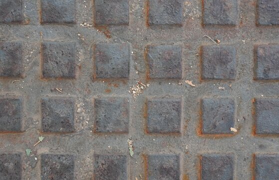 Weathered metal plate with raised square pattern and rust traces