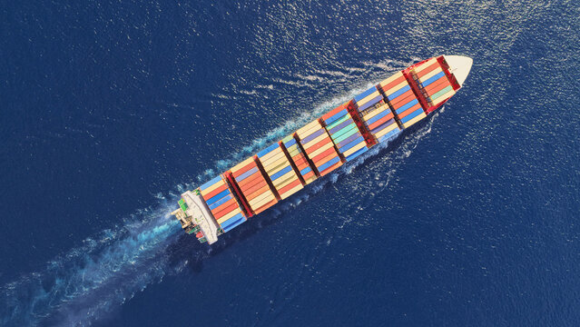 Aerial drone top down photo above huge size container ship cruising deep blue Mediterranean sea