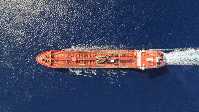 Aerial drone top down photo of small oil - chemical tanker cruising in deep blue open ocean sea