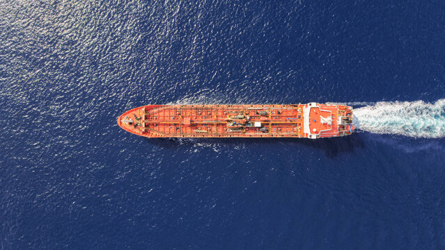 Aerial drone top down photo of small oil - chemical tanker cruising in deep blue open ocean sea