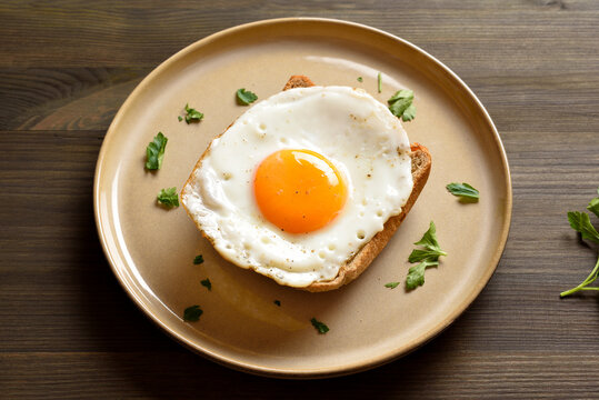 Fried egg on toast bread on wooden background