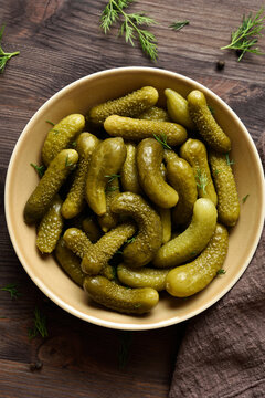 Pickled cucumbers in bowl on wooden background