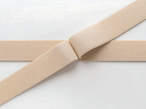 Beige elastic fabric band folded on a white background, showing textile texture and woven pattern for sewing, tailoring, and garment making