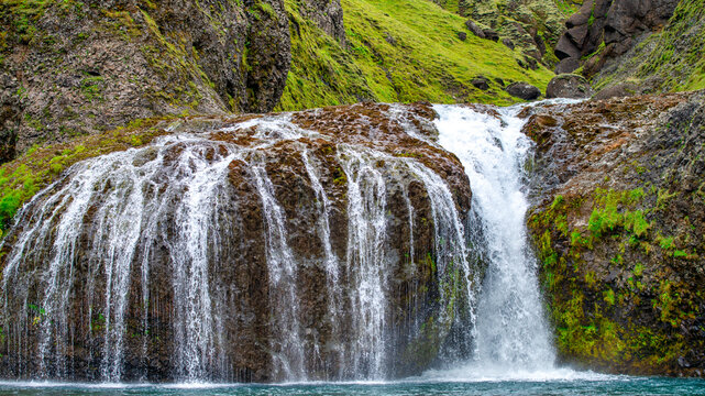 Iceland Stjornarfoss waterfall cascading into a rocky pool in summer