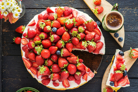 vanilla coconut cheesecake, decorated with fresh strawberries, a cup of aroma coffee on a table