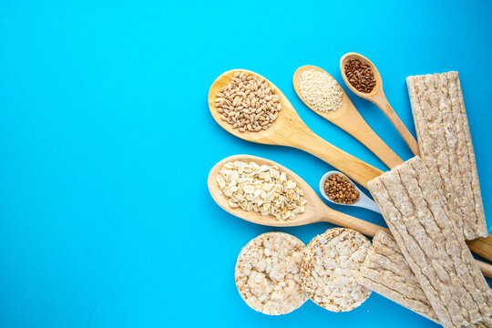 Healthy whole grain crispbreads and various seeds in wooden spoons  background. Healthy eating, diet food and weight loss concept.