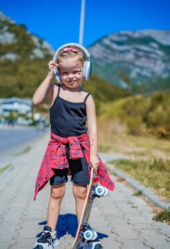 Full length portrait of stylish little skater girl with skateboard