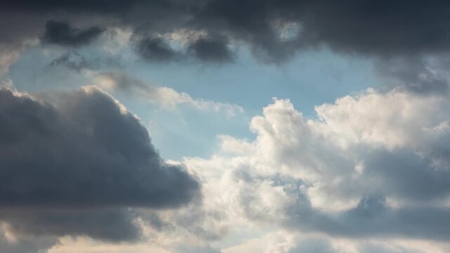 Timelapse of partly cloudy sky. White clouds rolling fast over blue sky.