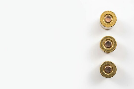 Brass bullet shell casings arranged on white background, metallic ammo details, firearm ammunition closeup