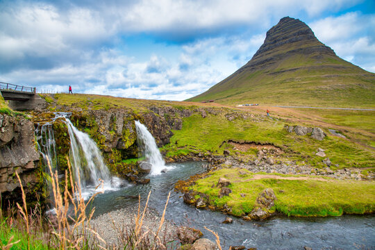 Kirkjufellsfoss waterfalls at summer sunset with panoramic Iceland landscape.