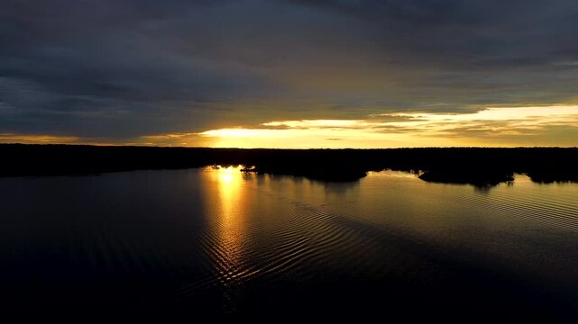 Golden Sunset Over Flooded Amazon Rainforest Lagoon in Ecuador, Calm Water, Sun Reflection, Dark Forest Silhouette and Remote Wetland Landscape