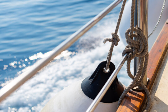 A boat sails through blue ocean water near Kerkira, Greece, showing ropes tied to metal railings. White water foam is generated as the vessel moves across the sea surface.   