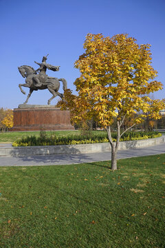 The equestrian statue of Amir Timur rises in the background behind a golden-leaved autumn tree in Amir Timur Square in Tashkent, Uzbekistan