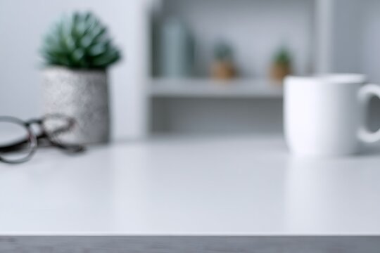 White office desk with blurred background including a mug and glasses. Modern workspace tabletop for product mockup. Clean and minimalist backdrop