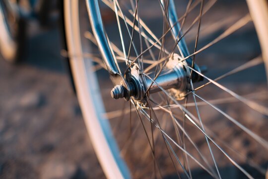 Close up of bicycle wheel hub and spokes in warm light. Metallic bike details outdoors
