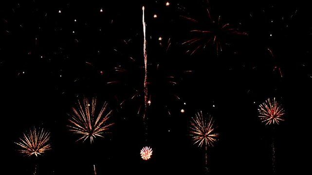 4K. loop seamless of real fireworks background golden shining fireworks with bokeh lights in the night sky. glowing fireworks show. New year's eve fireworks celebration multiple colors 