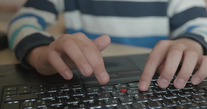 Close-up children's hands typing on laptop computer keyboard. 4K 10-bit