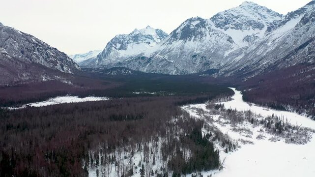 Drone Pan Over Winter Valley Basin and Snow-Capped Alpine Mountain Range