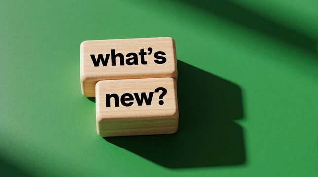 Wooden blocks with text whats new on green background. Cubes show question about latest updates products. Concept of innovation, discovery using timber cubes. Business idea for marketing news