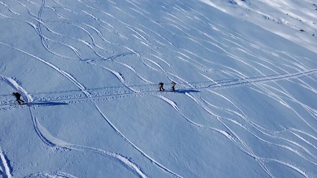 Aerial view of three ski tourers on a skin track in the Swiss Alps