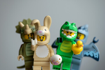 Obraz premium Lego minifigures animal-costume: a fun group featuring a crocodile, rabbit, pterodactyl, and triceratops on a gray background.