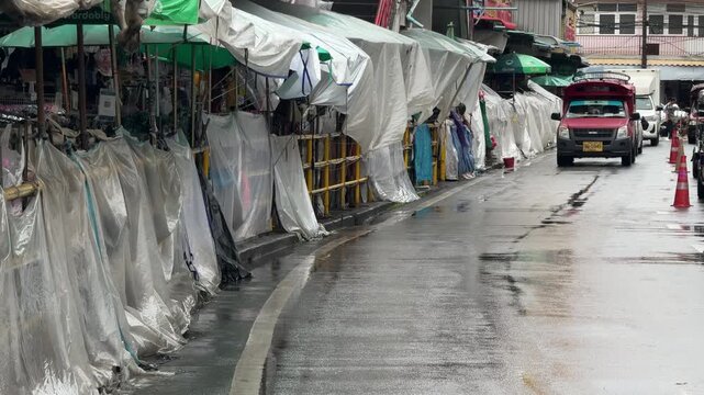 Market stalls covered in plastic on wet street in Chiang Mai