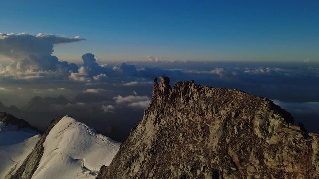 Aerial flight along a jagged summit ridge above a sea of clouds