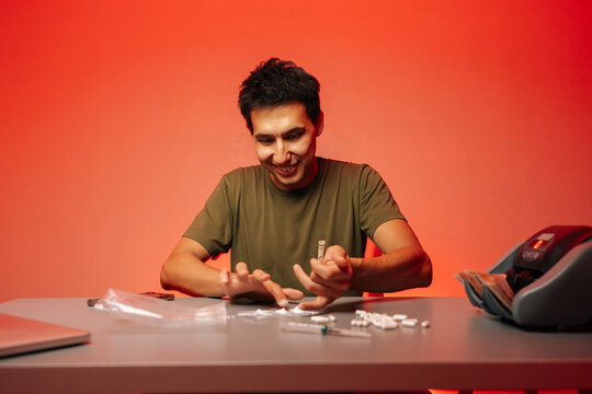 Criminal activity scene depicting illegal narcotics preparation, featuring cocaine lines, cash counter, pharmaceutical drugs, syringes, packaging materials on crimson surface.