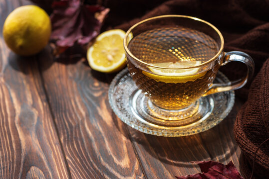 Warm glass cup of herbal tea with lemon slice on rustic wooden table cozy autumn scene